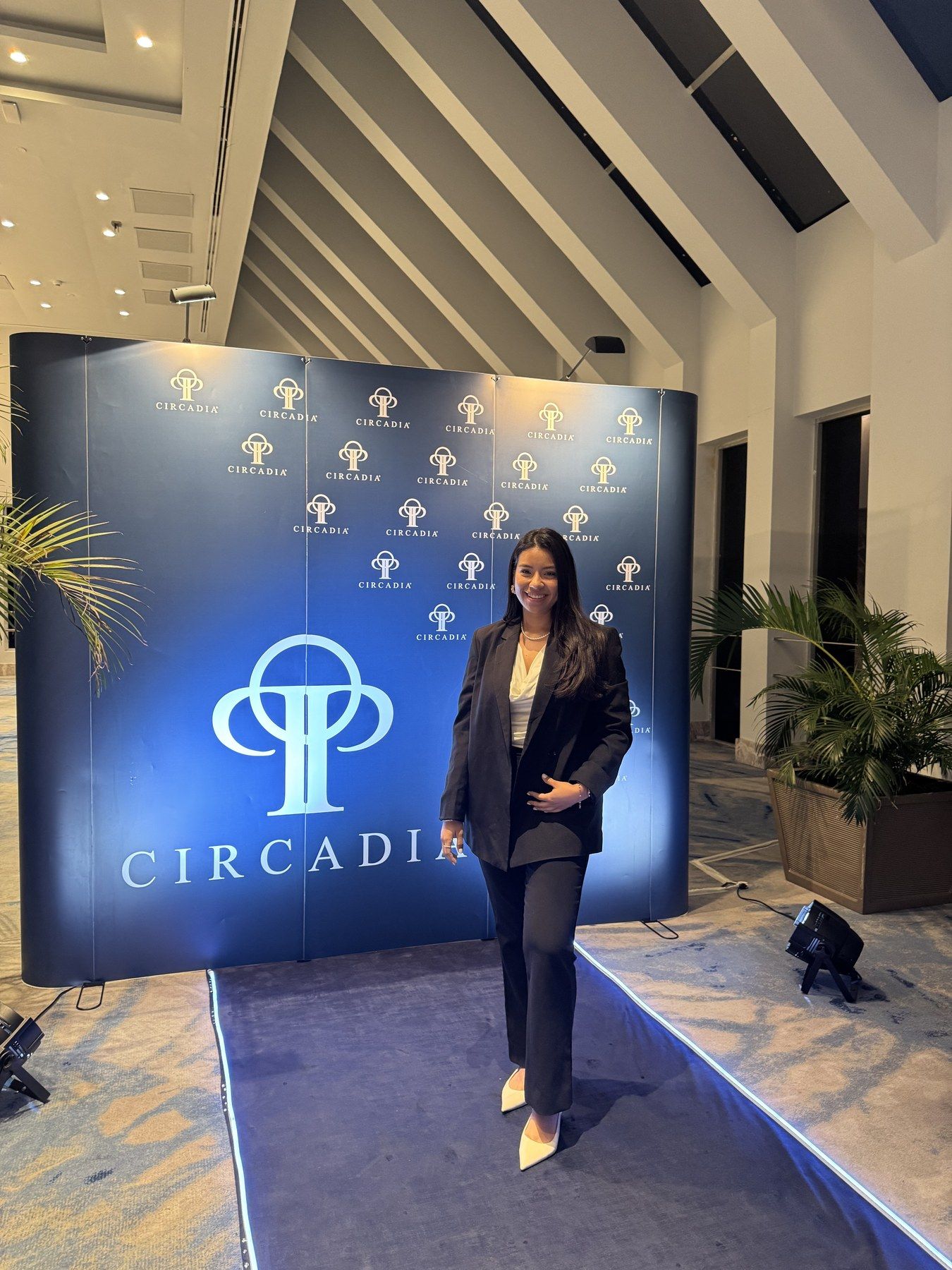 Ambar, con traje negro, frente al fondo con el logo de Circadia en un evento de la marca