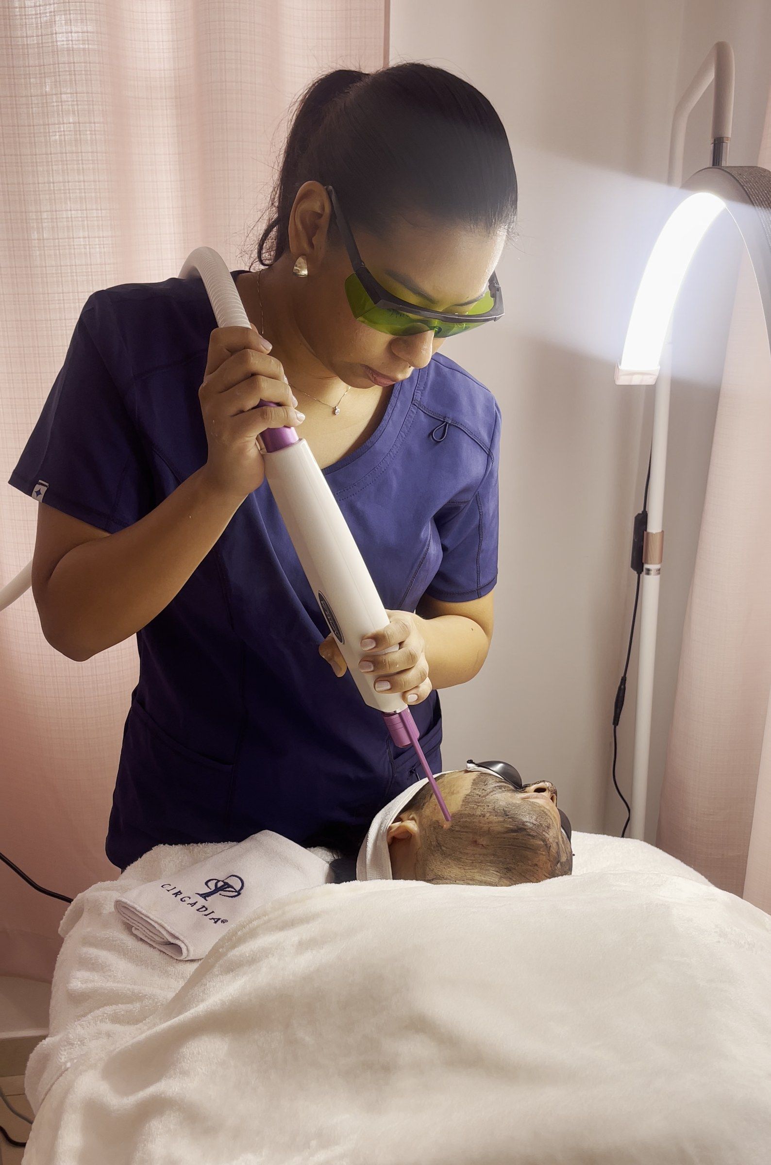 Ambar, con gafas de protección, aplica el láser del protocolo Pico Glow sobre el rostro de una clienta